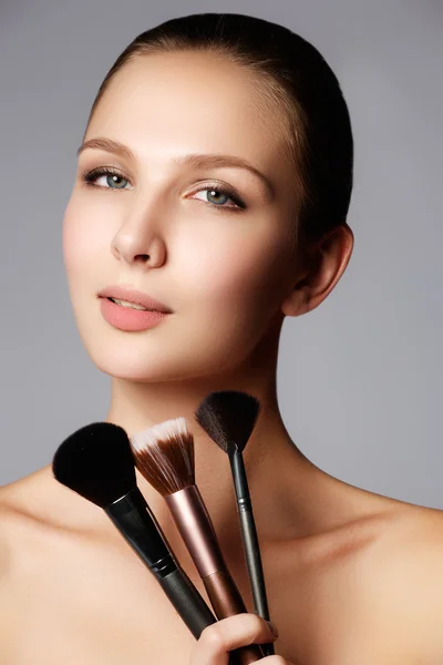 Chica de belleza con pinceles de maquillaje. Maquillaje Natural para Mujer Morena con Ojos Azules. Hermosa cara. Cambio de imagen. Piel perfecta. Aplicar maquillaje — Foto de Stock