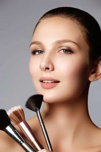 Modèle beauté avec pinceau de maquillage. Maquillage lumineux pour femme brune aux yeux bleus. Beau visage. Une peau parfaite. Appliquer le maquillage — Photo