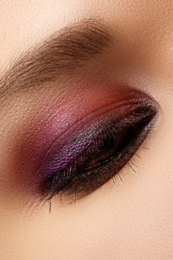 Kadının güzel göz, parlak ve derin renkler makyaj makro çekim. Göz kapağı üzerinde koyu mor göz farı. Seksi görünüm, şehvetli bak. Glamourous şık makyaj