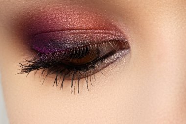 Kadının güzel göz, parlak ve derin renkler makyaj makro çekim. Göz kapağı üzerinde koyu mor göz farı. Seksi görünüm, şehvetli bak. Glamourous şık makyaj