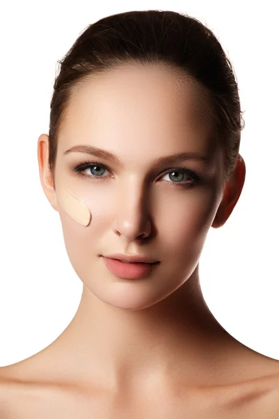 Bela cara de mulher jovem com fundação cosmética em uma pele. Conceito de tratamento de beleza. Maquiagem artista aplicando base tonal líquido no rosto da mulher. Foto de close-up da bochecha — Fotografia de Stock