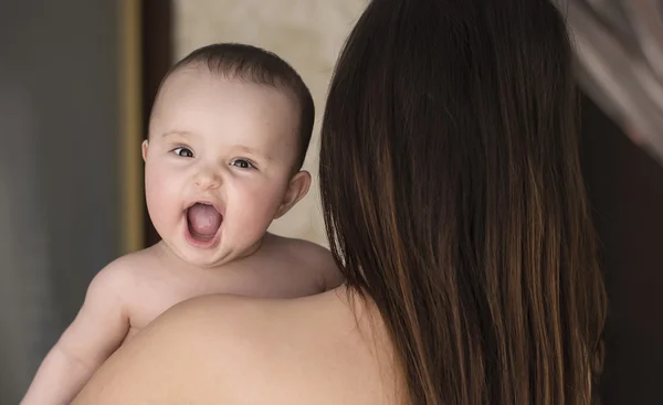 Usmívající se dítě v náručí své matky — Stock fotografie