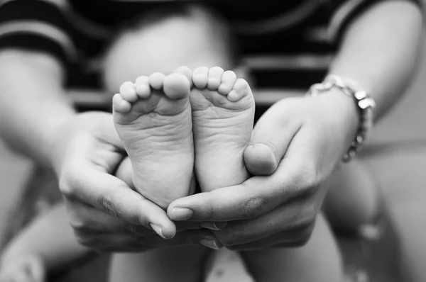 Pés de crianças pequenas nas mãos da mãe — Fotografia de Stock