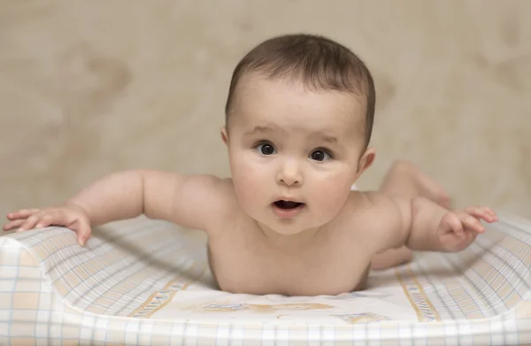 Bebê deitado de barriga erguendo as mãos — Fotografia de Stock