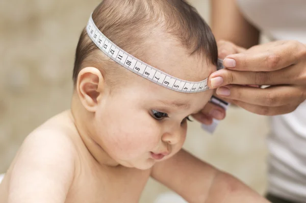 Mom measures the size of the head of a beautiful baby — Stock Photo, Image