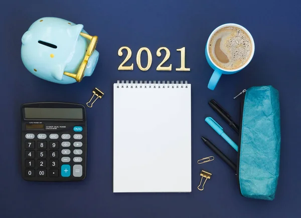 2021年の計画の概念 鉛筆ケース 空のメモ帳 貯金箱 カプチーノカップと青の背景に数字と机の上のビュー テキストのためのスペースのあるアイテムのフラットレイアウト — ストック写真