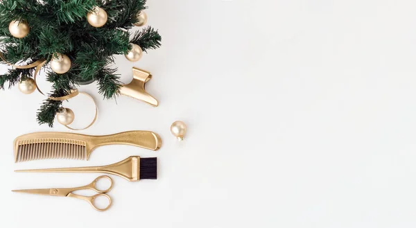 Altın rengi kuaför aletleri ve beyaz arka planda bir Noel ağacı olan afiş. Kuaför salonu aksesuarları ve mesaj için yeri olan bir tatil şablonu. Saç stilistinin makasıyla düz yatıyordu.
