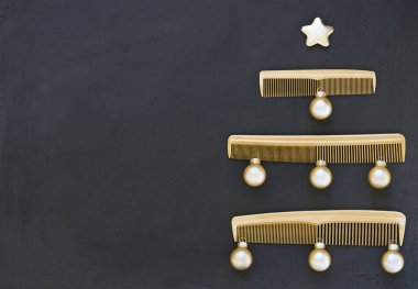 Koyu gri arka planda altın taraklardan yapılmış Noel ağacı. Mesaj atmak için yeri olan bir kuaför salonu için yılbaşı şablonu. Kuaför aksesuarlarıyla tatil afişi.