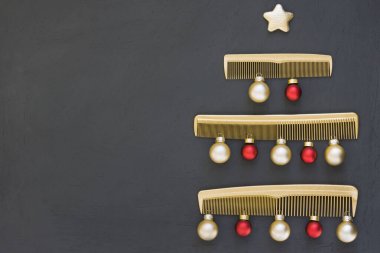 Koyu gri arka planda altın taraklardan yapılmış Noel ağacı. Mesaj atmak için yeri olan bir kuaför salonu için yılbaşı şablonu. Berber aksesuarlı tatil afişi.