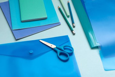 Mavi ofis malzemeleriyle donatılmış bir geçmiş. Dizin, defter, defter, aynı rengin farklı tonlarında kalem..