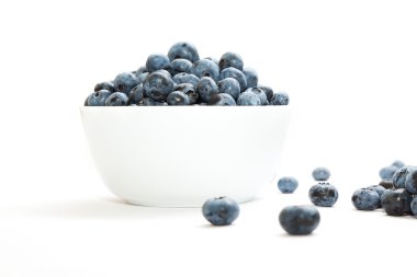 beyaz zemin üzerinde bir kasede yaban mersini