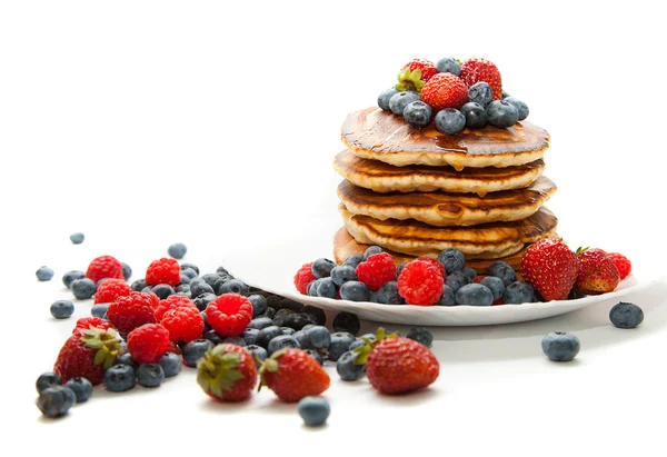 Pannkakor med honung och bär på vit bakgrund — Stockfoto