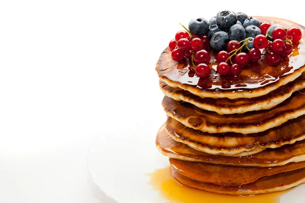 Pannkakor med honung och bär på vit bakgrund — Stockfoto