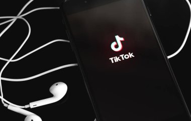 Ekran akıllı telefonunda TikTok logosu ve siyah arka planda Apple Kulaklıkları. TikTok video yaratmak ve paylaşmak için bir uygulamadır. Moskova, Rusya - 10 Haziran 2020