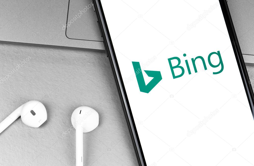 Bing app logo on the screen smartphone with headphones Earpods closeup. Bing is a web search engine owned and operated by Microsoft. Moscow, Russia - August 11, 2020