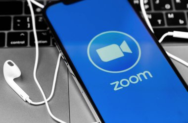Apple Earpod kulaklıklı ekrandaki iPhone uygulamasının logosunu yakınlaştır. Zoom Video Communications, uzaktan konferans hizmeti veren bir şirket. Moskova, Rusya - 3 Aralık 2020