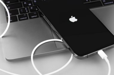 Apple iPhone akıllı telefonu Şimşek kablosu ile MacBook 'a bağlandı. Apple, online hizmetler tasarlayan, geliştiren, çok uluslu bir teknoloji şirketidir. Moskova, Rusya - 14 Ocak 2021