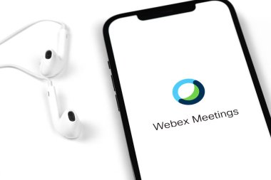 Webex Toplantı simgesi mobil uygulaması ekrandaki akıllı telefon iPhone ve kulaklıklar. Webex Toplantılar, bulut toplantısı veya video konferansı sunan popüler uygulamalardan biridir. Moskova, Rusya - 15 Ocak 2021