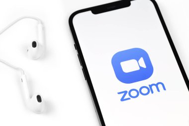 Apple Earpod kulaklıklı akıllı telefon iPhone ekranında zoom uygulaması logosu. Zoom Video Communications, uzaktan konferans hizmeti veren bir şirket. Moskova, Rusya - 16 Ocak 2021