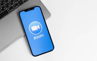Mobil uygulama logosunu Macbook defterli akıllı telefon iPhone 'una yakınlaştır. Zoom Video Communications, uzaktan konferans hizmeti veren bir şirket. Moskova, Rusya - 12 Ocak 2021