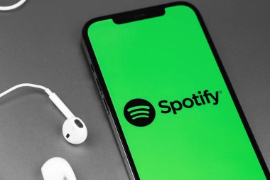 Mobil logo uygulamasını kulaklıklı akıllı telefon iPhone 'unda kulaklıkla kapat. Spotify - çevrimiçi ses servisi. Moskova, Rusya - 11 Mart 2021