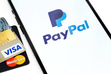 Visa, MasterCard plastik elektronik kartlar ve ekranda PayPal logosu olan akıllı telefon. Visa and MasterCard, Amerika Birleşik Devletleri 'nin çok uluslu finansal hizmet şirketidir. Moskova, Rusya - 16 Nisan 2021