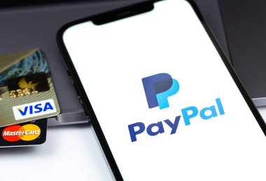 Visa, MasterCard plastik elektronik kartlar, ekranda PayPal logosu olan akıllı telefon. Visa and MasterCard, Amerika Birleşik Devletleri 'nin çok uluslu finansal hizmet şirketidir. Moskova, Rusya - 16 Nisan 2021