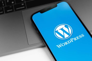 WordPress logosu ekranda, akıllı telefon, iPhone MacBook klavye kapanışı. WordPress - açık kaynak içerik yönetim sistemi. Moskova, Rusya - 11 Nisan 2021