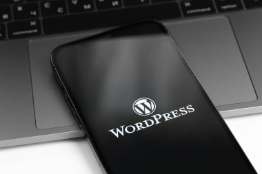 WordPress logosu ekran akıllı telefonunda, iPhone MacBook klavyeli yakın plan. WordPress - açık kaynak içerik yönetim sistemi. Moskova, Rusya - 11 Nisan 2021