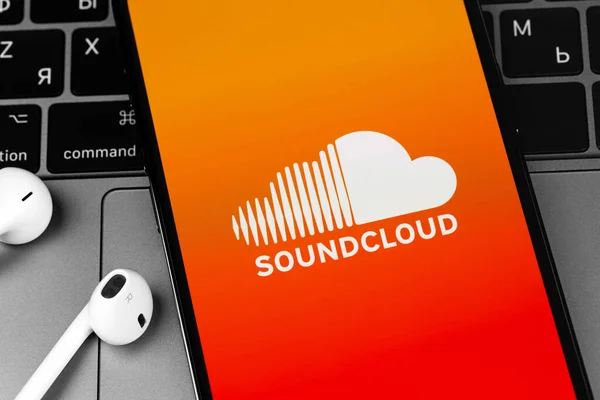 Earpodsで画面スマートフォンのIphone上のSoundcloudロゴモバイルアプリは ヘッドフォンを閉じます Soundcloudはグローバルなオンラインオーディオ配信プラットフォームです モスクワ ロシア 2021年3月11日 — ストック写真