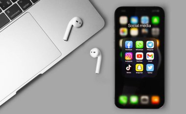 showing social media apps Facebook, WhatsApp, YouTube, Instagram, TikTok, Snapchat, Gmail, Telegram, Twitter - apps on screen smartphone iPhone with AirPods, Macbook closeup. Moscow, Russia - June 14, 2021