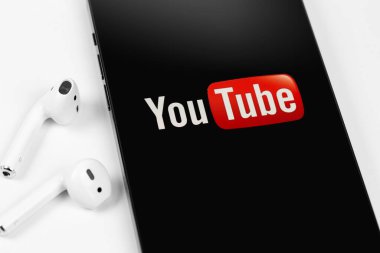 Youtube mobil logo uygulaması akıllı telefon iPhone 'unda AirPods kulaklıkları ile yakın plan. YouTube herkesin izleyebileceği ücretsiz bir video paylaşım uygulamasıdır. Moskova, Rusya - 12 Haziran 2021