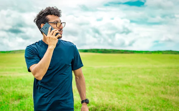 Man calling by cell phone, young man in the field calling by cell phone