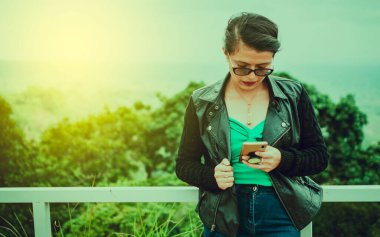 Latin bir kadın cep telefonunu kontrol ediyor, gözlüklü güzel bir kız cep telefonunu kontrol ediyor.