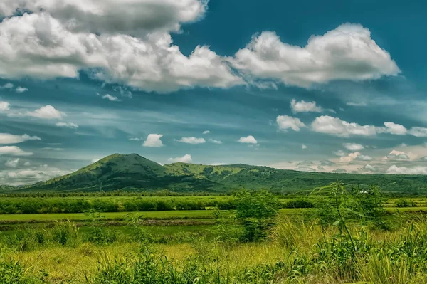 Image of a green field with mountains with clouds and blue sky, Mountains with clouds and blue sky