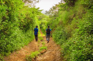 Kırsalda bir yolda iki adam, iki genç adam fotokopi alanı olan bir yolda yürüyorlar.