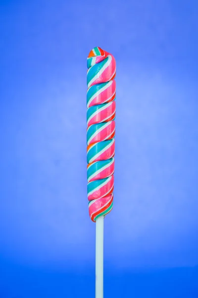 Lízátko ve tvaru tyče na modrém pozadí — Stock fotografie