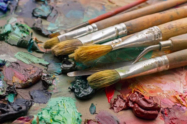 Pinceles usados en la paleta de un artista de pintura al óleo de colores para el dr — Foto de Stock