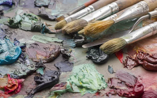 Pinceles usados en la paleta de un artista de pintura al óleo de colores para el dr —  Fotos de Stock