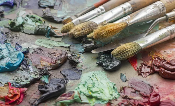 Används borstar i en konstnärs palett av färgglada oljefärg för dr — Stockfoto