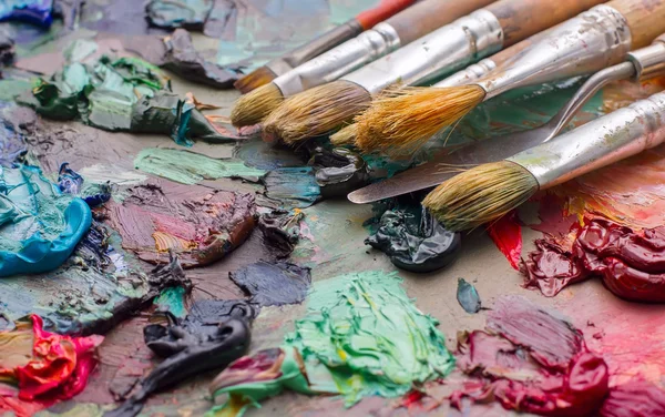 Pincéis usados na paleta de uma artista de tinta colorida a óleo para o dr — Fotografia de Stock