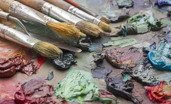 Pincéis usados na paleta de uma artista de tinta colorida a óleo para o dr — Fotografia de Stock