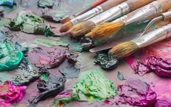 Pincéis usados na paleta de uma artista de tinta colorida a óleo para o dr — Fotografia de Stock