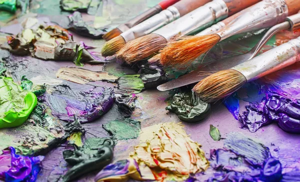 Pincéis usados na paleta de uma artista de tinta colorida a óleo para o dr — Fotografia de Stock