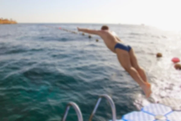 Мужчина прыгает с понтонного моста в воду, спортивные леи — стоковое фото
