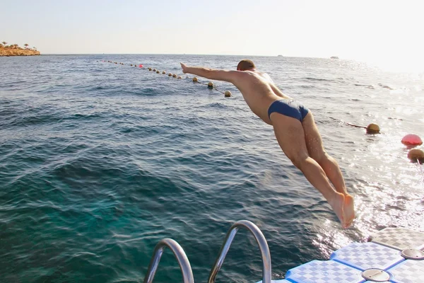 Un hombre saltando desde el puente de pontón en el agua, sport leis —  Fotos de Stock