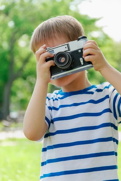Happy cheerful boy with a camera, the baby photographed outdoors — Stock Photo, Image
