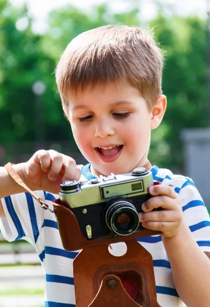 Menino alegre feliz com uma câmera, o bebê fotografado ao ar livre — Fotografia de Stock