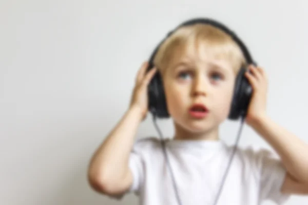 Счастливый веселый мальчик с наушниками, слушающий музыку на белом фоне , — стоковое фото