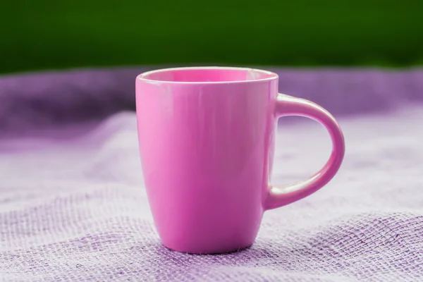 Розовая чашка на столе у окна на мешковине изолированы, с — стоковое фото